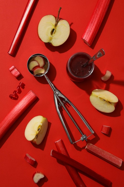 Łyżka rabarbaru słoik z dżemem i jabłkiem na czerwonym tle flatlay