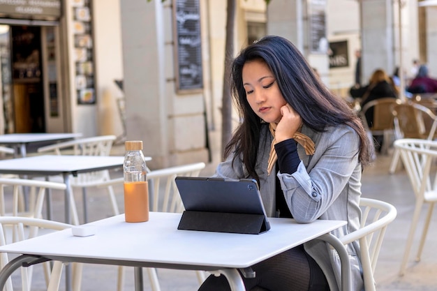 M?oda sprzedawczyni azjatyckich patrz?c na tablet Kobieta kierownik wykonawczy sekretarz pracy z tabletem w restauracji na zewn?trz Portret