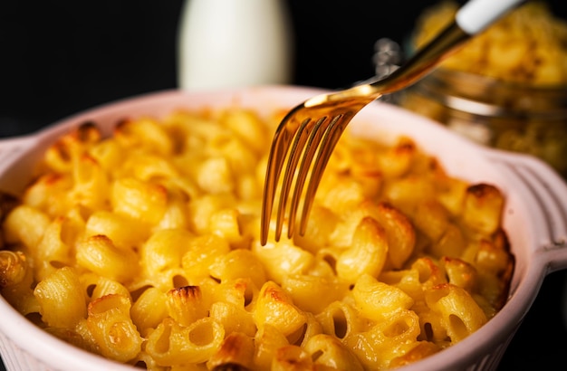 Mac and cheese, makaron makaron w stylu amerykańskim w sosie serowym na ciemnym tle. Zdjęcie wysokiej jakości