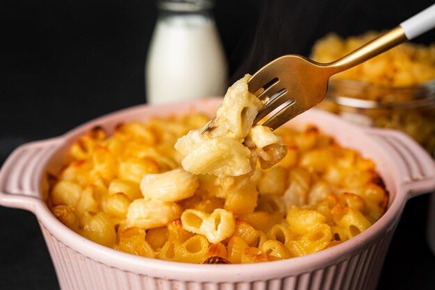 Mac and cheese, makaron makaron w stylu amerykańskim w sosie serowym na ciemnym tle. Zdjęcie wysokiej jakości