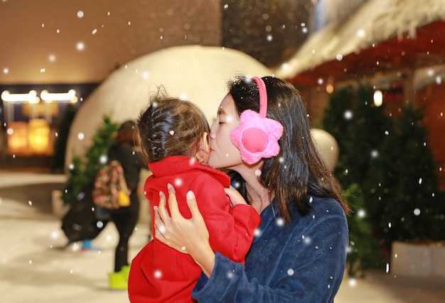 Macierzysty całowanie jej córka w śniegu, zima czas.