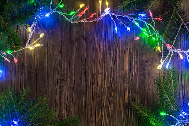 Magiczna świąteczna girlanda z jasnymi światłami i jodłowymi gałęziami na drewnie
