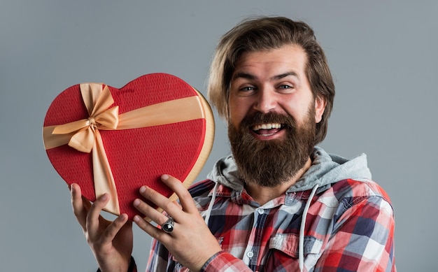 Magiczny wygląd mężczyzna na randkę miłosną przystojny hipster z prezentem szczęśliwy walentynki urodziny zakupy brutalny brodaty mężczyzna w kraciastej koszuli dojrzały facet z brodą słyszeć kształt prezent