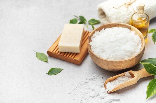 Magnesium flakes in a wooden bowl with soap towel and essential oil creating a relaxing spa scene