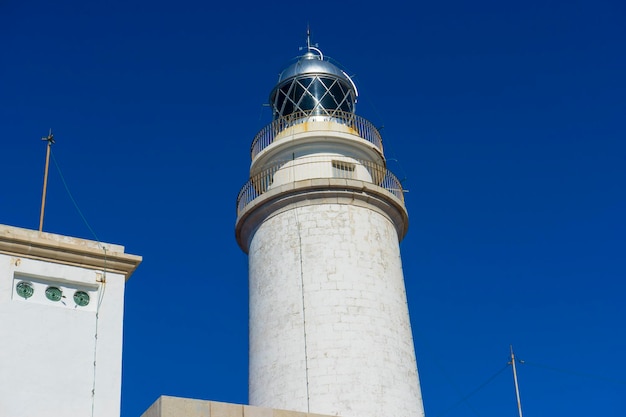Majorka, latarnia morska nad Morzem Śródziemnym, błękitne niebo bez chmur ze spokojną wodą. służy do ostrzegania statków o obecności skał