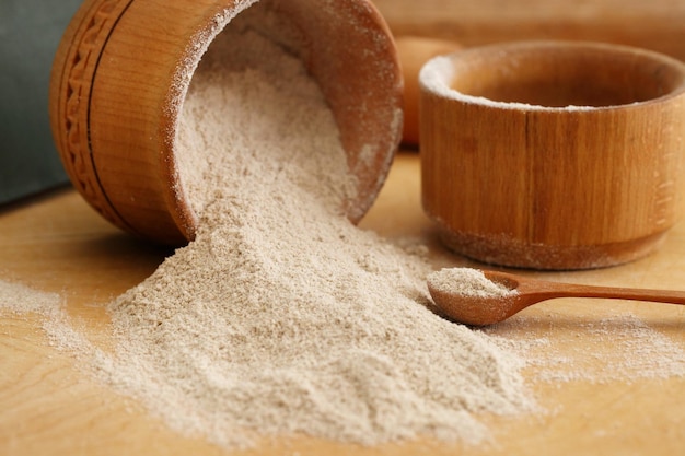 Mąka sezamowa w glinianej misce na drewnianym tle