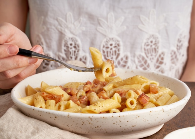 Makaron Carbonara. Kobieta Siedzi Przy Stole I Je Makaron Penne Z Pancettą,