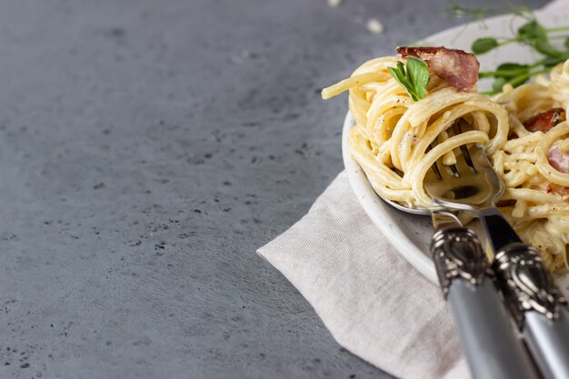 Makaron Carbonara, spaghetti z boczkiem, jajkiem, parmezanem i sosem śmietanowym na talerzu ceramicznym