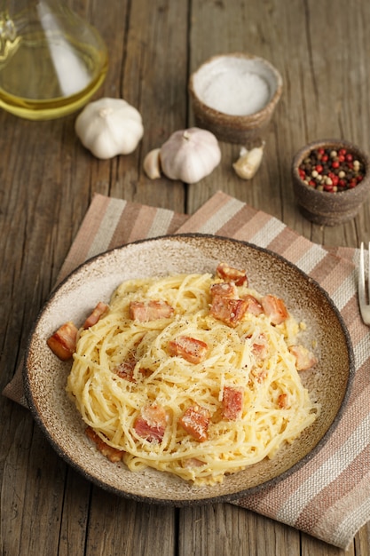 Zdjęcie makaron carbonara. spaghetti z boczkiem, jajkiem, parmezanem. widok z boku, pionowa, kuchnia włoska.