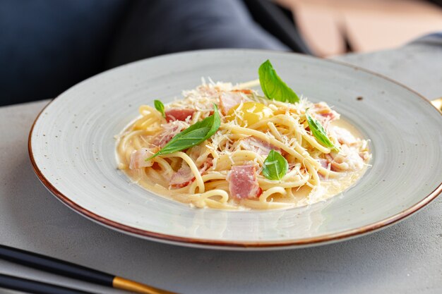 Makaron Carbonara z boczkiem i śmietaną podawany na talerzu z bliska