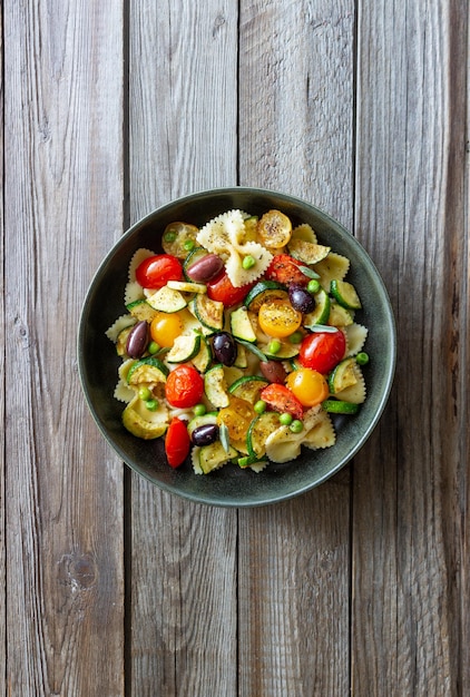 Makaron farfalle z pomidorami cukinia groszek oliwki kalamata i szałwia zdrowe odżywianie wegetariańskie