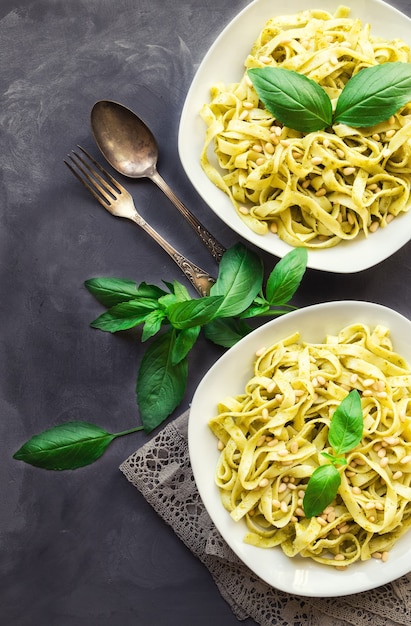 makaron fettuccine z sosem pesto bazylią i orzeszkami pinii na betonowym tle kuchnia włoska