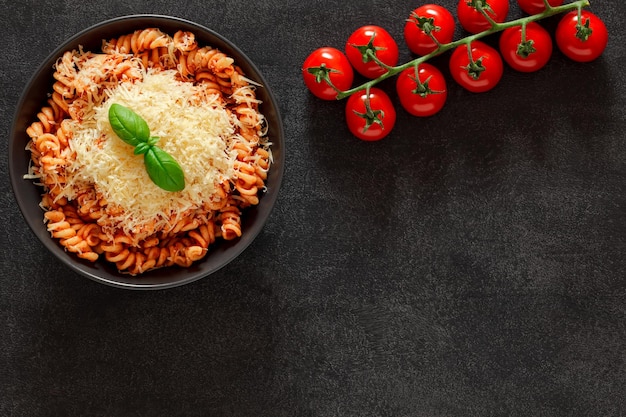 Makaron Fusilli Gotowany Z Sosem Pomidorowym Tartym Parmezanem I Zielonym Liściem Bazylii Gałązką Pomidorków Koktajlowych Na Ciemnym Tle Widok Z Góry Miejsce Na Skopiowanie Tekstu