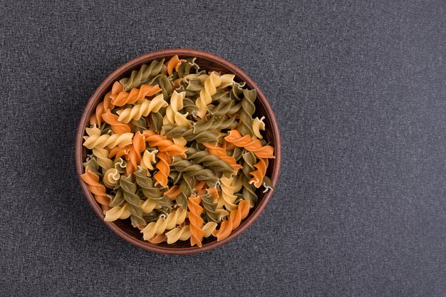 Makaron Fusilli w misce na szarym tle. Surowy włoski makaron. Widok z góry. Skopiuj miejsce Szablon. makieta