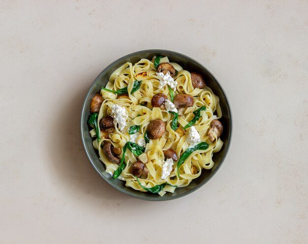 Makaron Linguine z pieczarkami, białym serem, szpinakiem i czosnkiem. Zdrowe odżywianie. Jedzenie wegetariańskie. Dieta.