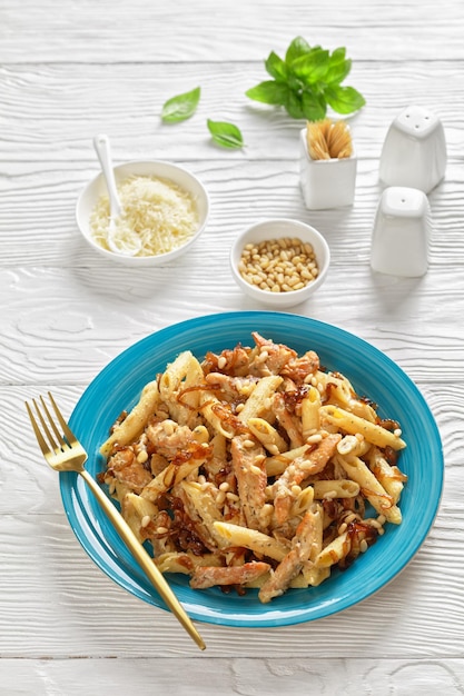 Zdjęcie makaron penne alfredo z kurczakiem z karmelizowaną cebulą