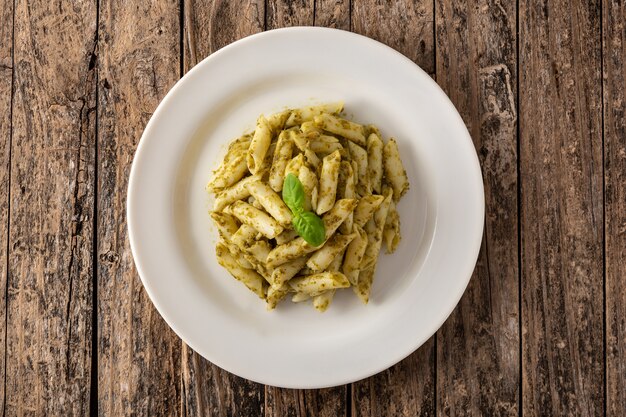 Makaron penne z sosem pesto na drewnianym stole