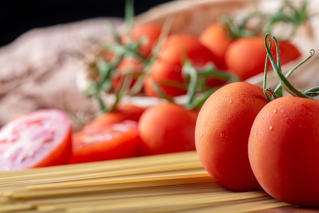 Makaron piękne szczegóły czerwonych pomidorów i pasma surowego spaghetti nad rustykalnym, selektywnym skupieniem drewna