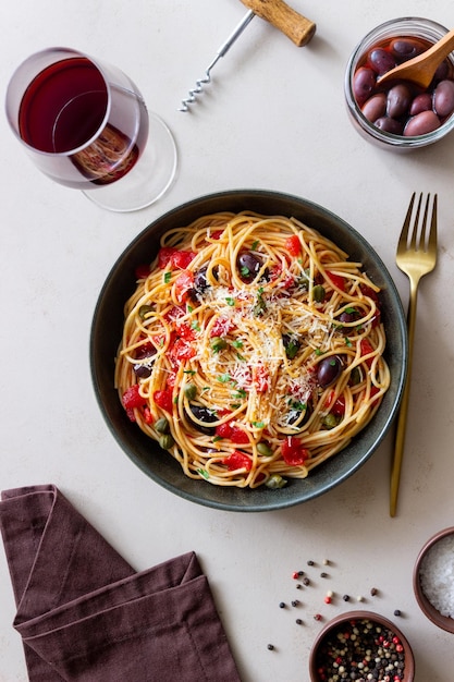 Makaron spaghetti Alla Puttanesca z kaparami Kalamata oliwki ser pomidory i anchois włoskie jedzenie