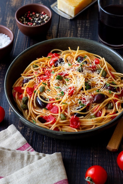 Makaron spaghetti Alla Puttanesca z kaparami Kalamata oliwki ser pomidory i anchois włoskie jedzenie