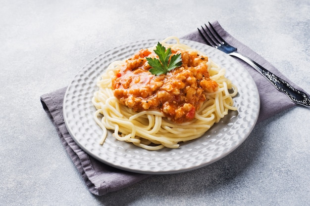 Makaron spaghetti Bolognese na białej płytce, szary stół