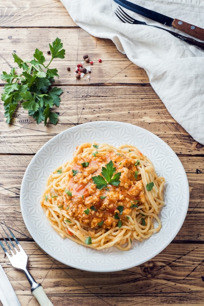 Makaron spaghetti Bolognese na białym talerzu, drewniany stół