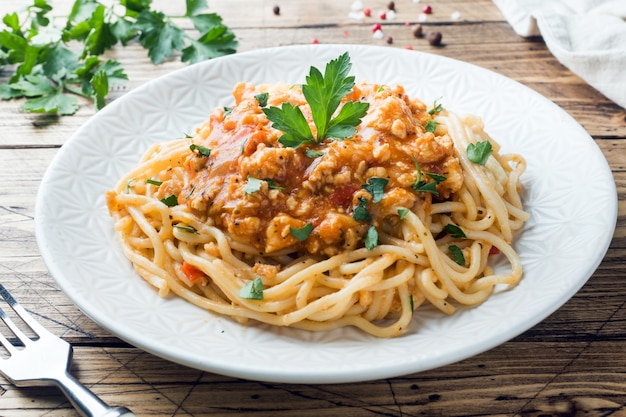 Makaron spaghetti Bolognese na białym talerzu, drewniany stół