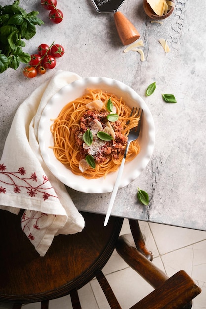 Makaron spaghetti Bolognese Smaczne apetyczne włoskie spaghetti z sosem bolońskim sos pomidorowy ser parmezan i bazylia na białym talerzu na szarym tle kamiennego lub betonowego stołu Widok z góry