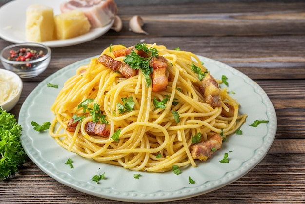 Makaron spaghetti carbonara z serem pancetta bekon jajko parmezan na drewnianym tle Włoskie jedzenie z bliska