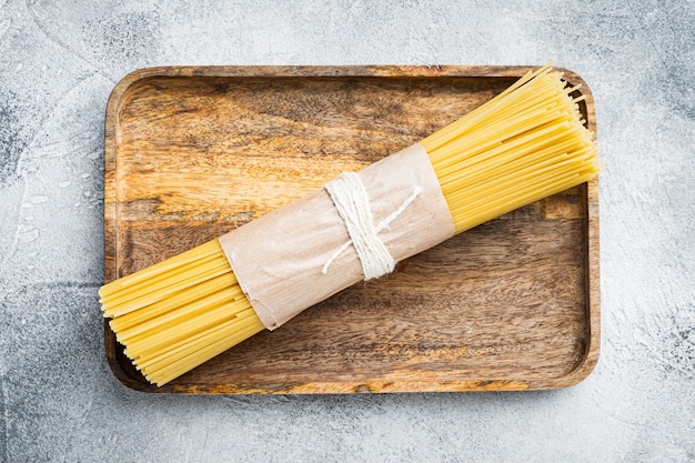Makaron spaghetti suszony, na drewnianej tacy, na szaro