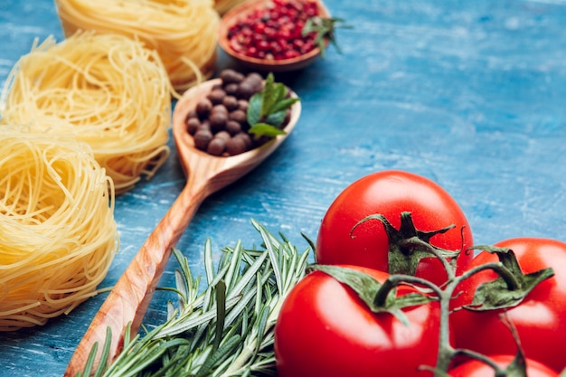 Makaron spaghetti, warzywa i przyprawy, na drewnianym stole