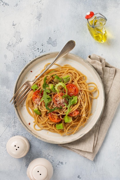 Makaron spaghetti z pesto, awokado i pomidorami w rustykalnym białym talerzu. Koncepcja surowego wegańskie jedzenie. Widok z góry.