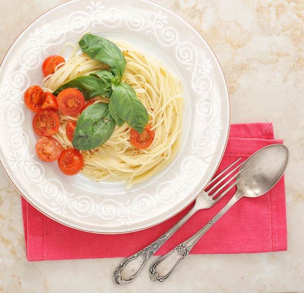 Makaron spaghetti z pomidorami koktajlowymi i bazyliką w talerzu