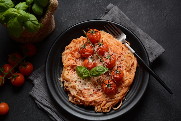 Makaron spaghetti z pomidorkami koktajlowymi przyozdobionym listkiem bazylii