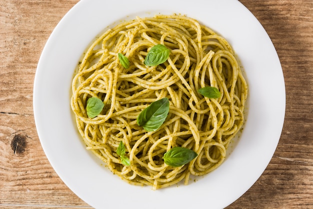 Makaron spaghetti z sosem pesto na drewnianym stole