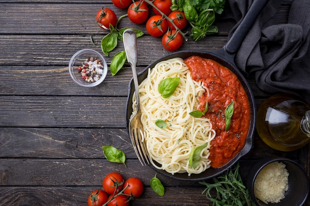 Makaron spaghetti z sosem pomidorowym i bazylią na drewnianym stole