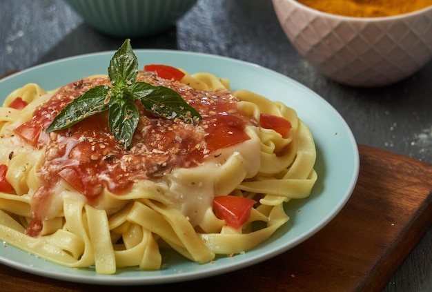 makaron tagliatelle Spaghetti en salsa de tomate en un plato turquesa de madera y base negra.