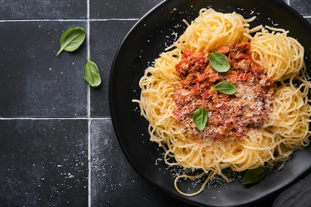 Makaron tagliatelle z klopsikami w sosie pomidorowym z bazylią i parmezanem na czarnym kamiennym lub betonowym tle Tradycyjne włoskie danie i kuchnia Widok z góry z kopią miejsca