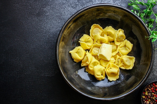 Makaron tortellini nadziewany ravioli na czarnej misce