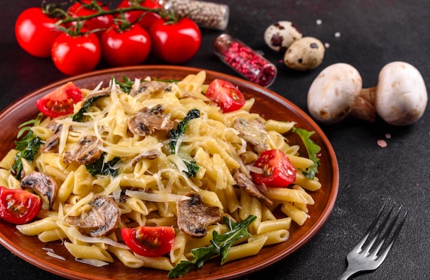 Makaron z grzybami, serem, szpinakiem, rukkola i pomidorami koktajlowymi. Włoskie danie, kultura śródziemnomorska