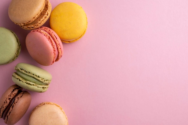 Makaroniki kolorowe ciasteczka Macarons francuski słodki deser widok z góry różowe tło Kopiuj przestrzeń