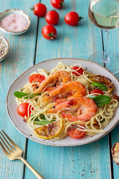 Makaronowe spaghetti z krewetkami, pomidorami, czosnkiem, szpinakiem i cytryną. Kuchnia włoska. Owoce morza. Dieta.