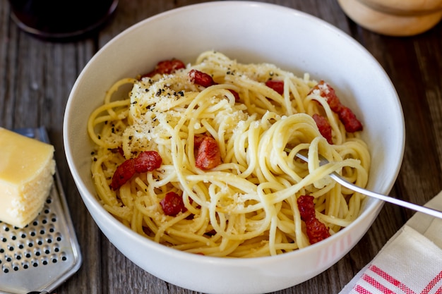 Makaronu spaghetti carbonara na drewnianym stole. Kuchnia włoska. Przepis. Styl rustykalny. Wino.