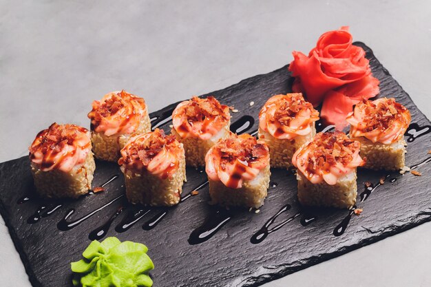 Maki Sushi Rolls z łososiem na czarnym kamieniu na ciemnym tle. Z imbirem i wasabi. Menu sushi. Japońskie jedzenie. Zbliżenie na pyszne japońskie jedzenie z rolką sushi. Poziome zdjęcie.