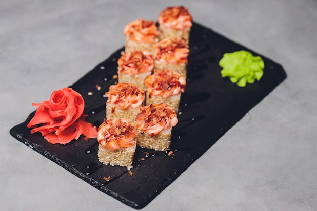 Maki Sushi Rolls z łososiem na czarnym kamieniu na ciemnym tle Z imbirem i wasabi Menu sushi Japońskie jedzenie Zbliżenie pyszne japońskie jedzenie z rolką sushi Zdjęcie poziome