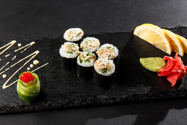 Maki Sushi Rolls z wakame i sosem orzechowym na czarnym kamieniu w ciemności