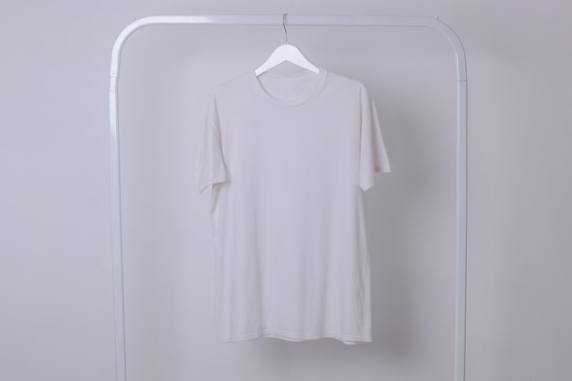 Makieta białej podstawowej koszulki wiszącej na wieszaku na ubrania