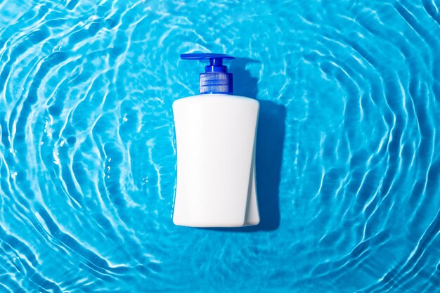Makieta białej tubki z produktem kosmetycznym do nawilżania w wodzie na niebieskim tle do projektowania