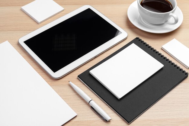 Makieta cyfrowego tabletu z notatnika, materiałów eksploatacyjnych i filiżankę kawy na pulpicie.