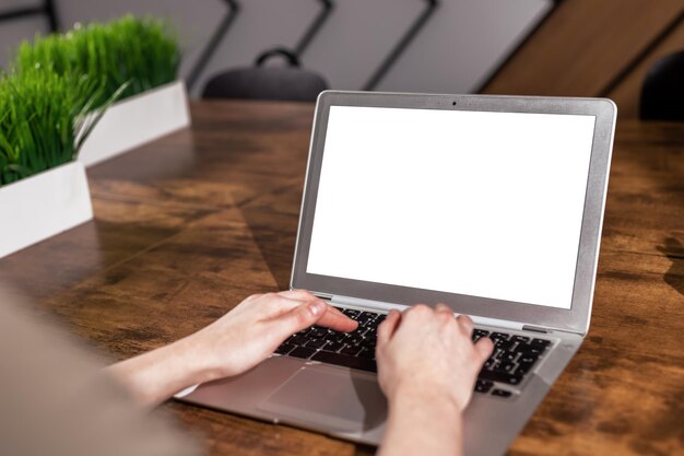 Makieta ekranu laptopa i ręczne wpisywanie Wyświetlacz komputera makieta z białym pustym tłem na drewnianym biurku
